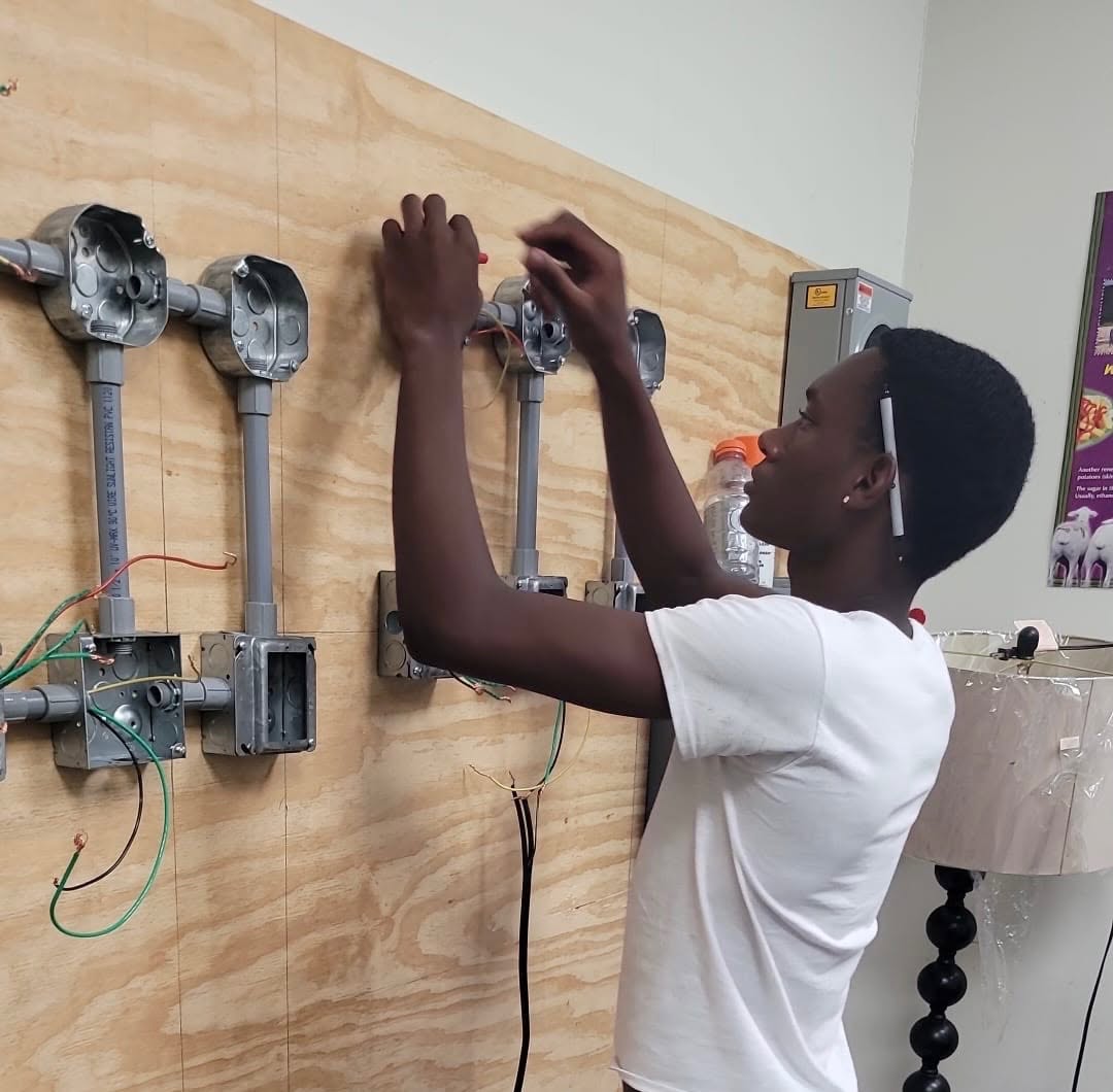 Learners practising electrical wiring on a training board