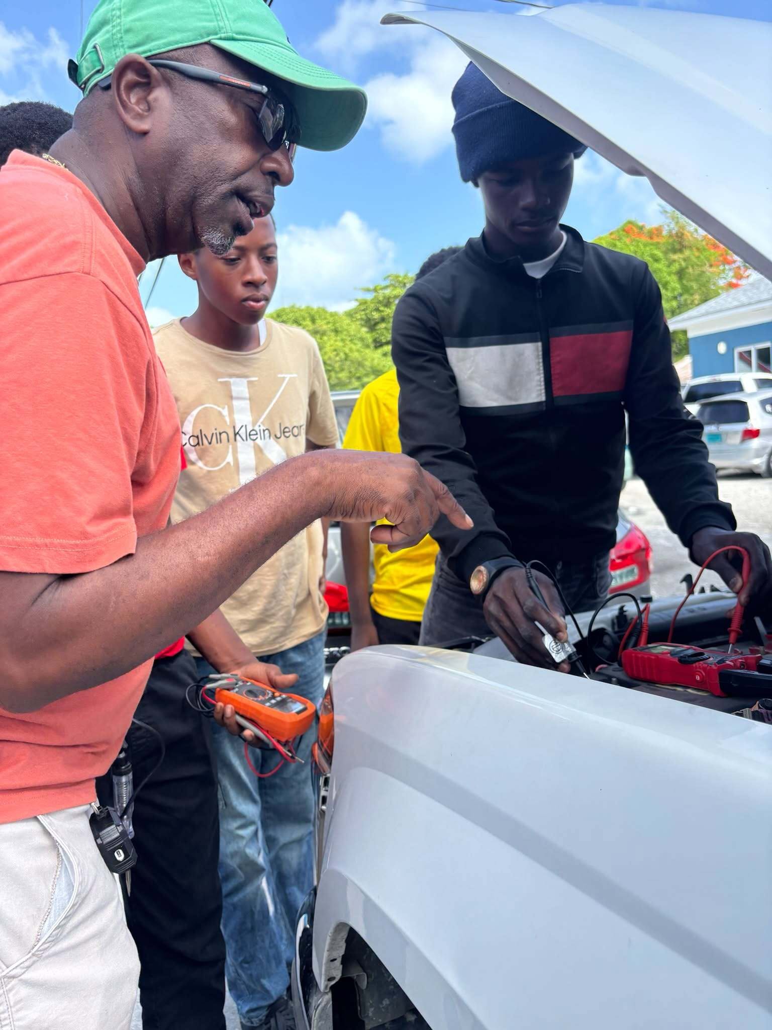 A mentor and learners using equipment at a vehicle